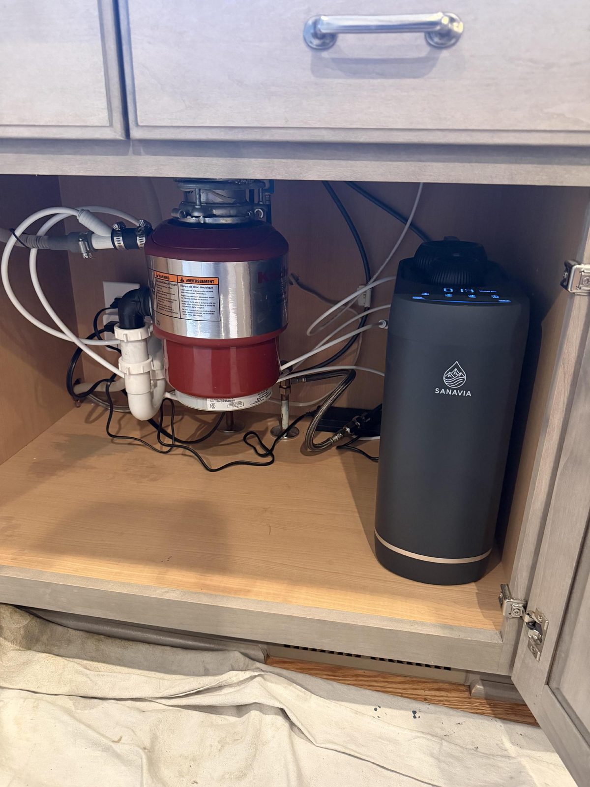 The Sanavia Hydra in place in a under-sink cabinet, with the drain lines run neatly to one side