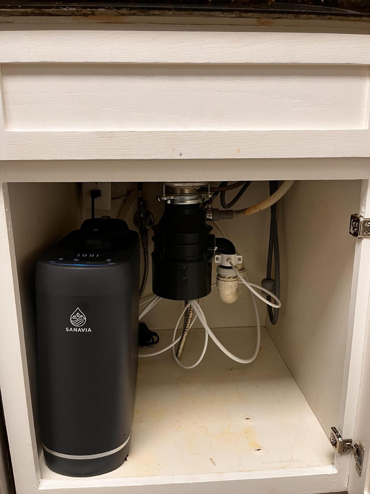 A Sanavia Hydra reverse osmosis system installed under a kitchen sink, next to the waste disposal