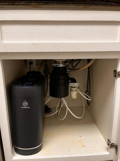 A Sanavia Hydra reverse osmosis system installed under a kitchen sink, next to the waste disposal