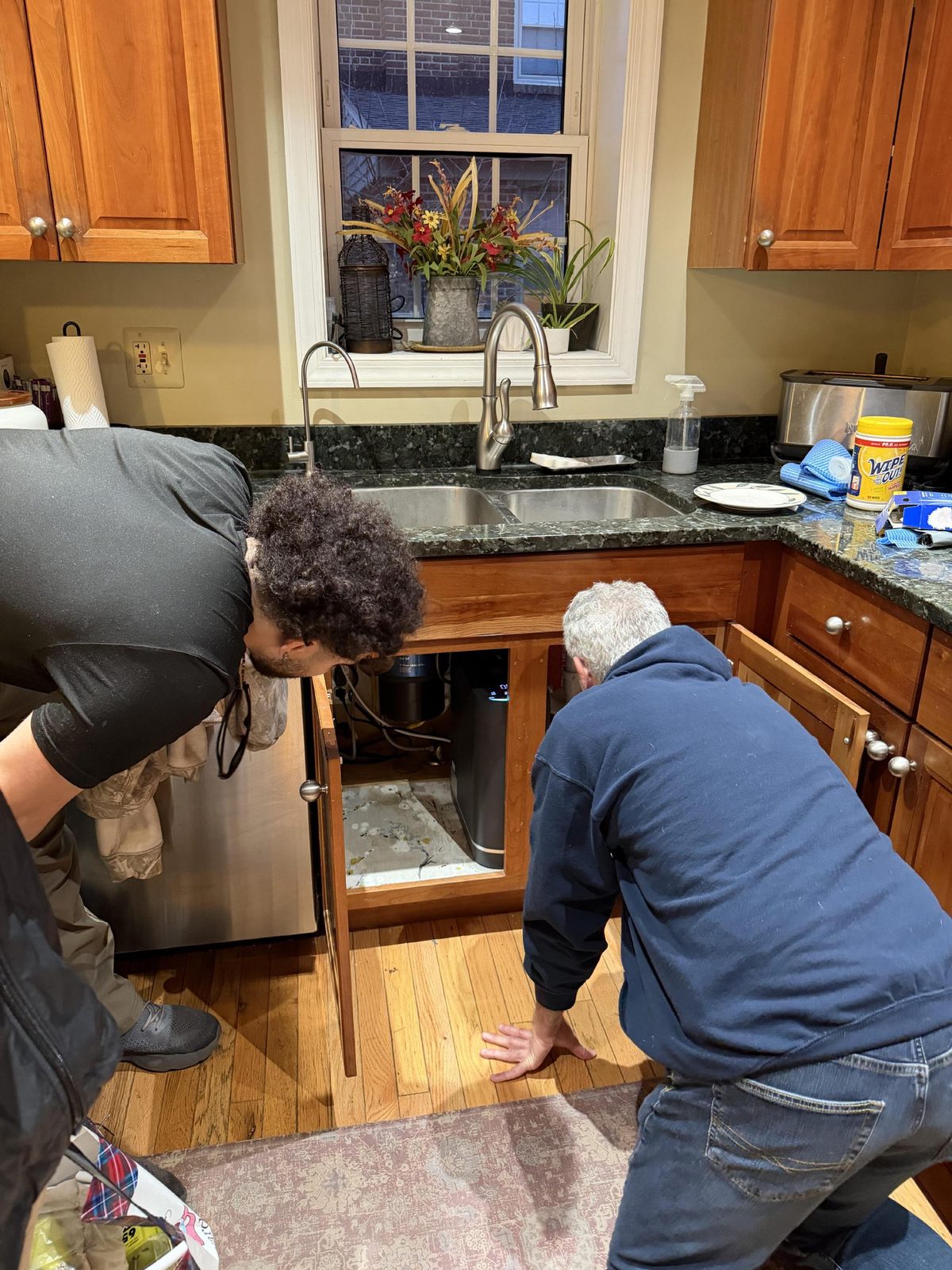 A Sanavia installer fitting a Hydra reverse osmosis system under a customer's kitchen sink